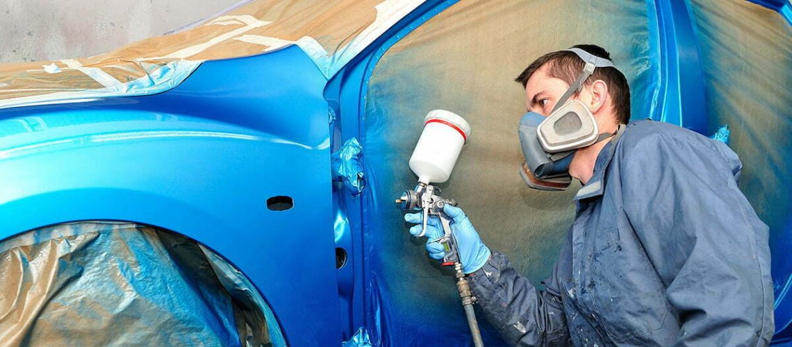 Painter working with blue car.