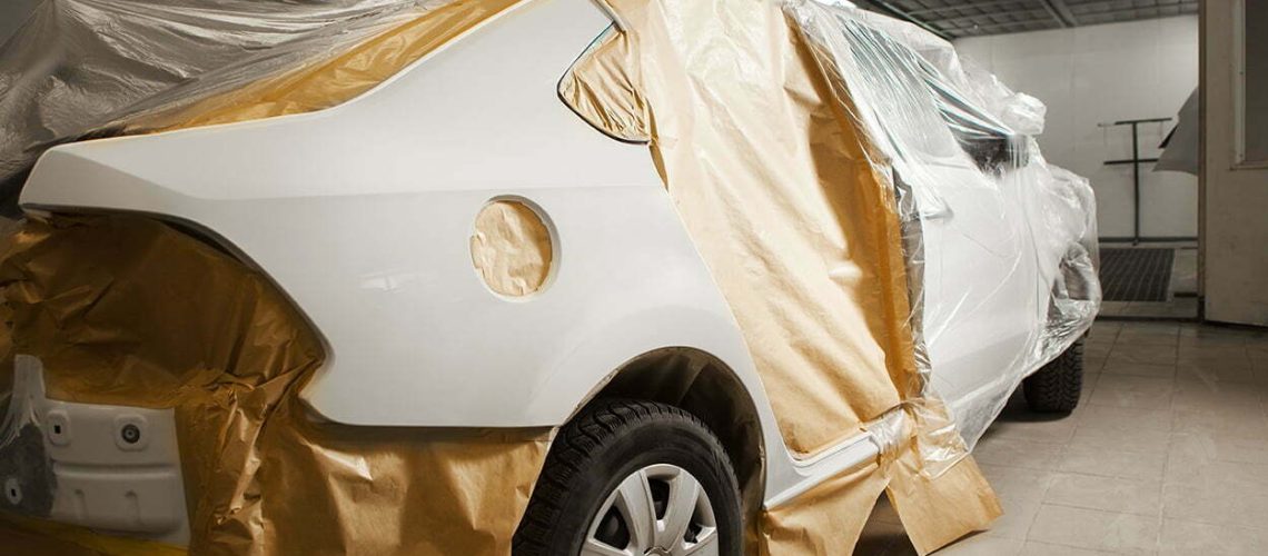 Garage painting car service. vehicle cover with protective paper before painting. Repairing car body work after accident.